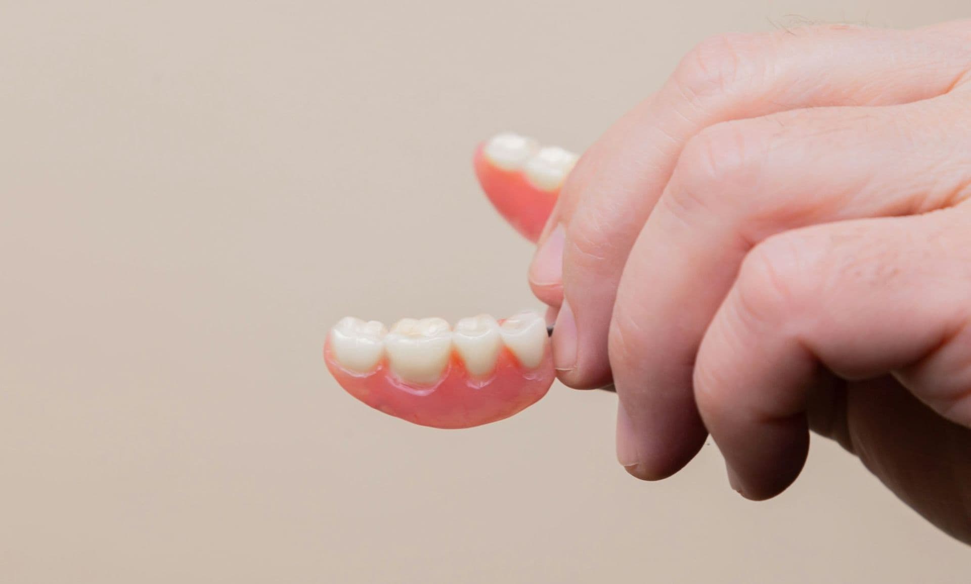 Iemand houdt een uitneembare gebitsprothese vast